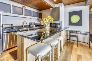 a kitchen with a counter with a sink and some chairs at Luxury 2 Bedroom Mountain Vacation Rental In The Heart Of Downtown Aspen One Block From Silver Queen Gondola in Aspen