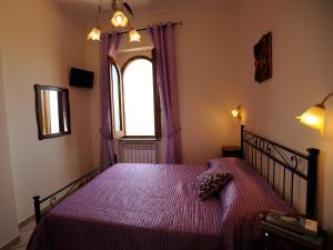 ein Schlafzimmer mit einem Bett mit einer lila Bettdecke und einem Fenster in der Unterkunft Villa dei Fantasmi in Rocca di Papa