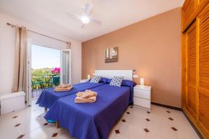 Schlafzimmer mit einem Bett mit blauer Bettwäsche und einem Fenster in der Unterkunft Apartamento Socorro 39-1 in Felanitx