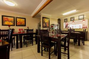 a dining room with tables and chairs in a restaurant at @Home Guest House in Rustenburg