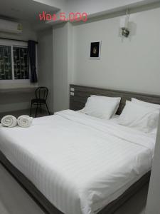 a bedroom with a large white bed with two towels on it at The grace kok udom in Prachin Buri