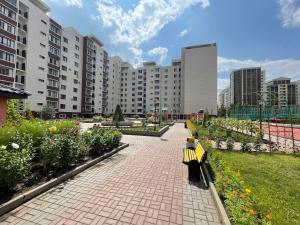 ein Park mit einer Bank, Blumen und Gebäuden in der Unterkunft Жилой Комплекс Акжайык in Astana