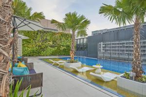 an outdoor pool with palm trees and lounge chairs at Citadines Connect City Centre Singapore in Singapore