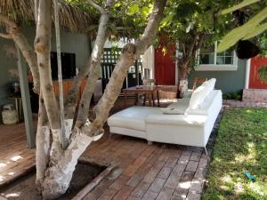 un sofá blanco sentado en un patio junto a un árbol en De Alamo hostel, en Rosarito