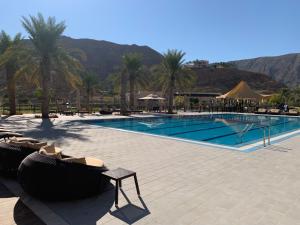 a large swimming pool with chairs and a resort at Stylish Apartment with a Jacuzzi (Park&Pool View) in Muscat
