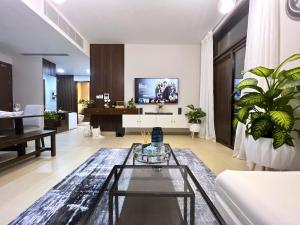 Stylish Apartment with a Jacuzzi (Park&Pool View) في مسقط: غرفة معيشة مع تلفزيون على الحائط