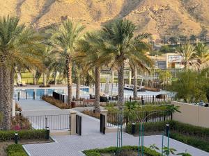 a resort with palm trees and a mountain in the background at Stylish Apartment with a Jacuzzi (Park&Pool View) in Muscat