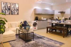 a living room with a couch and a table and a kitchen at Stylish Apartment with a Jacuzzi (Park&Pool View) in Muscat