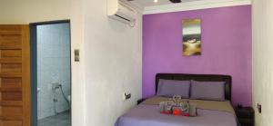 a bedroom with purple walls and a bed with sandals on it at OCEAN LODGE in Pantai Cenang