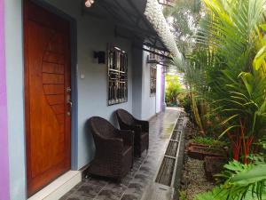 eine Veranda mit Korbstühlen und einer Holztür in der Unterkunft OCEAN LODGE in Pantai Cenang