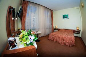 ein Hotelzimmer mit einem Bett und einem Tisch mit Blumen in der Unterkunft Hotel Astoria City Center in Iaşi