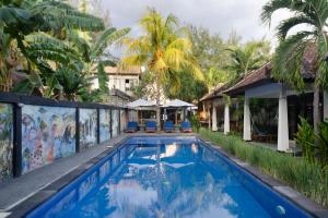a swimming pool in front of a house with palm trees at Warna Beach Hotel in Gili Trawangan