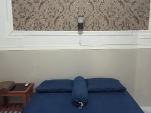 łóżko z niebieską poduszką w pokoju w obiekcie Cahaya Homestay w mieście Magelang