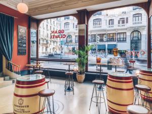 a bar with stools and barrels in front of a window at Iberostar Las Letras Gran Via in Madrid