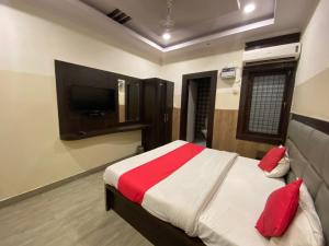 - une chambre avec un lit doté d'oreillers rouges et une télévision dans l'établissement Hotel Nagpal By WB Inn, à Haridwar