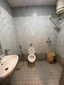 La salle de bains est pourvue de toilettes blanches et d'un lavabo. dans l'établissement Hotel Nagpal By WB Inn, à Haridwar