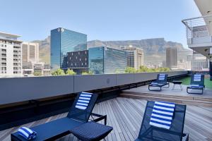 um terraço no último piso com cadeiras e vista para a cidade em Lovely 2 bedroom rental unit close to the V&A Waterfront em Cidade do Cabo