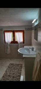baño con lavabo y ventana con cortinas en A cà du Sepino a due passi dal mare, en Carloforte