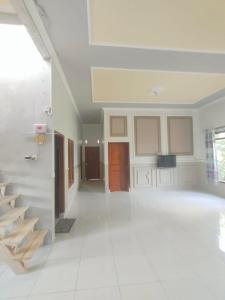 a large room with white tile floors and a staircase at Cahaya Homestay in Magelang