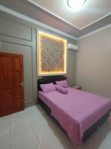 a bedroom with a purple bed and a window at Cahaya Homestay in Magelang