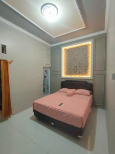 a bedroom with a pink bed and a window at Cahaya Homestay in Magelang