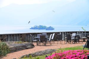 eine Gruppe von Stühlen und Tischen vor dem Wasser in der Unterkunft Hotel Collinetta in Ascona