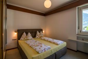 una camera da letto con letto, cuscini e finestra di Theatre Lodge Attico teatro a Merano
