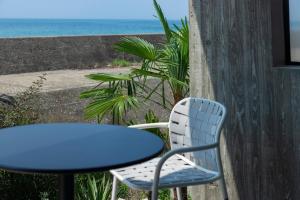 a blue table and a chair and the ocean at KAMOME SLOW HOTEL in Awaji