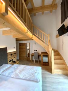 a bedroom with a bed and a wooden staircase at Hotel Chalet Alaska in Pozza di Fassa