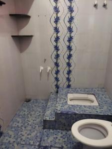 a bathroom with a toilet with a blue tile floor at Hidden gem home stay -2 in Madikeri