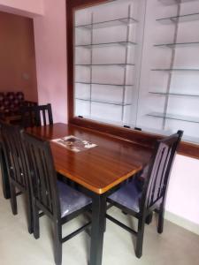 mesa de comedor con sillas y ventana en Hidden gem home stay -2, en Madikeri