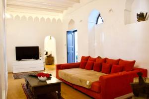 sala de estar con sofá rojo y TV en The House of Royals, en Zanzíbar