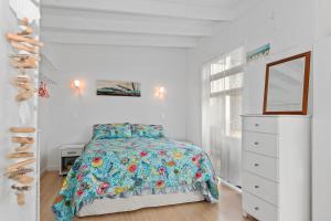 a white bedroom with a bed and a dresser at Bayside Beauty - Matapouri Holiday Home in Matapouri