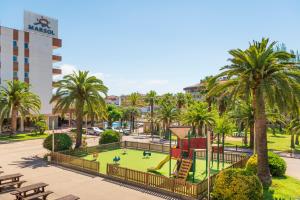 un parc avec une aire de jeux et des palmiers dans l'établissement Aparthotel Costa Encantada, à Lloret de Mar