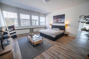 a bedroom with a bed and a living room with windows at Pit Stop Apartments in Cham