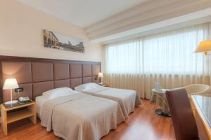 アレッツォにあるホテル ミネルヴァのベッド2台と窓が備わるホテルルームです。