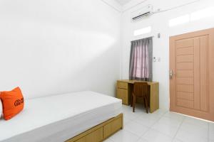 a bedroom with a bed with a orange pillow and a door at KoolKost Syariah @ Wisma Arafah Tasikmalaya (Minimum Stays 30 Nights) in Tasikmalaya