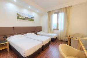 una camera d'albergo con due letti e un tavolo di Hotel Minerva ad Arezzo