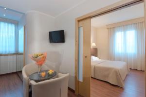 Cette chambre comprend un lit et une table avec un vase de fleurs. dans l'établissement Hotel Minerva, à Arezzo