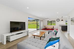 sala de estar con sofá y TV en Beach Haven - Karikari Peninsula Holiday Home en Karikari Peninsula