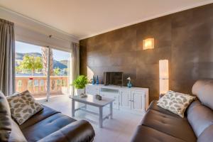 een woonkamer met een bank, een tv en een tafel bij Ideal Property Mallorca - Lago Miguel in Port d'Alcudia