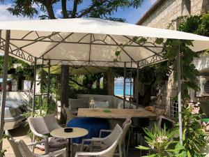 patio con tavolo e sedie sotto un ombrellone bianco di Apartments by the sea Supetar, Brac - 11497 a Supetar (San Pietro di Brazza)
