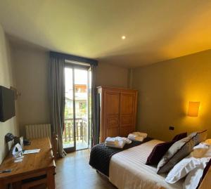 a bedroom with a bed and a desk and a window at Chaberton Lodge & Spa in Sauze dʼOulx