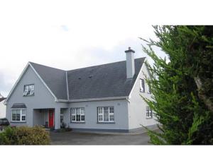 a white house with a black roof at Derghaven B&B, Hostel & Self Catering in Scarriff