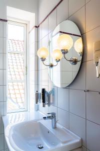 ein Bad mit einem Waschbecken, einem Spiegel und einem Fenster in der Unterkunft Hotel & Restaurant Brauner Hirsch Osterwieck in Osterwieck