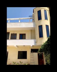 a white building with blue windows and a staircase at Fati Guest House in Durrës