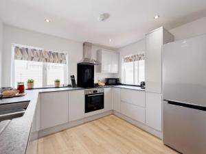 cocina con armarios blancos y fogones en Salters Cottage - Stunning Modernised 3 BR Home Just Steps From the Beach, en Budleigh Salterton