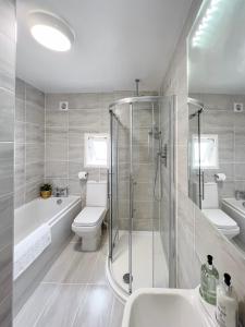 a bathroom with a shower and a toilet and a sink at Salters Cottage - Stunning Modernised 3 BR Home Just Steps From the Beach in Budleigh Salterton