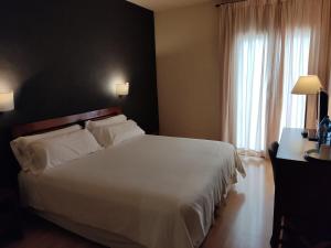 a bedroom with a large white bed and a window at Puerta De España in La Jonquera