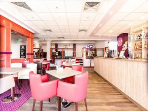 a restaurant with pink chairs and tables and a bar at Kegworth Hotel East Midlands Airport in Castle Donington
